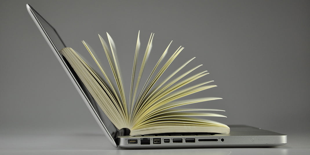 An image of a laptop with paper pages coming out of it