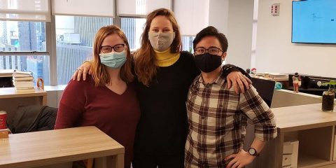 Three people wearing masks standing in an office