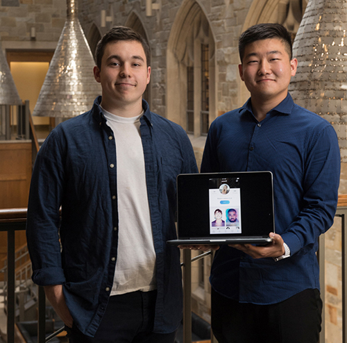 two student pose in Fulton Atrium with a laptop that displays their startup's website