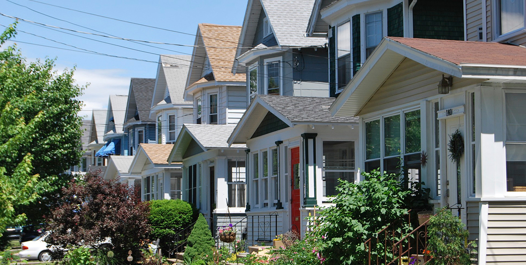 a row of houses with bushes and trees in the front yards