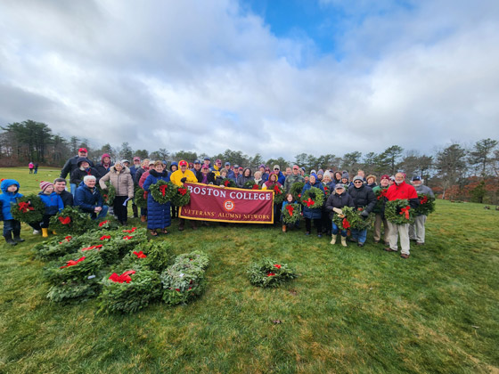 Veterans Alumni Network participants pose with a Boston College banner during a Wreaths Across America cerimony