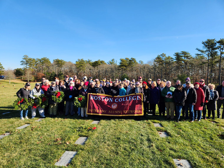 Veterans Alumni Network participants pose with a Boston College banner during a Wreaths Across America cerimony