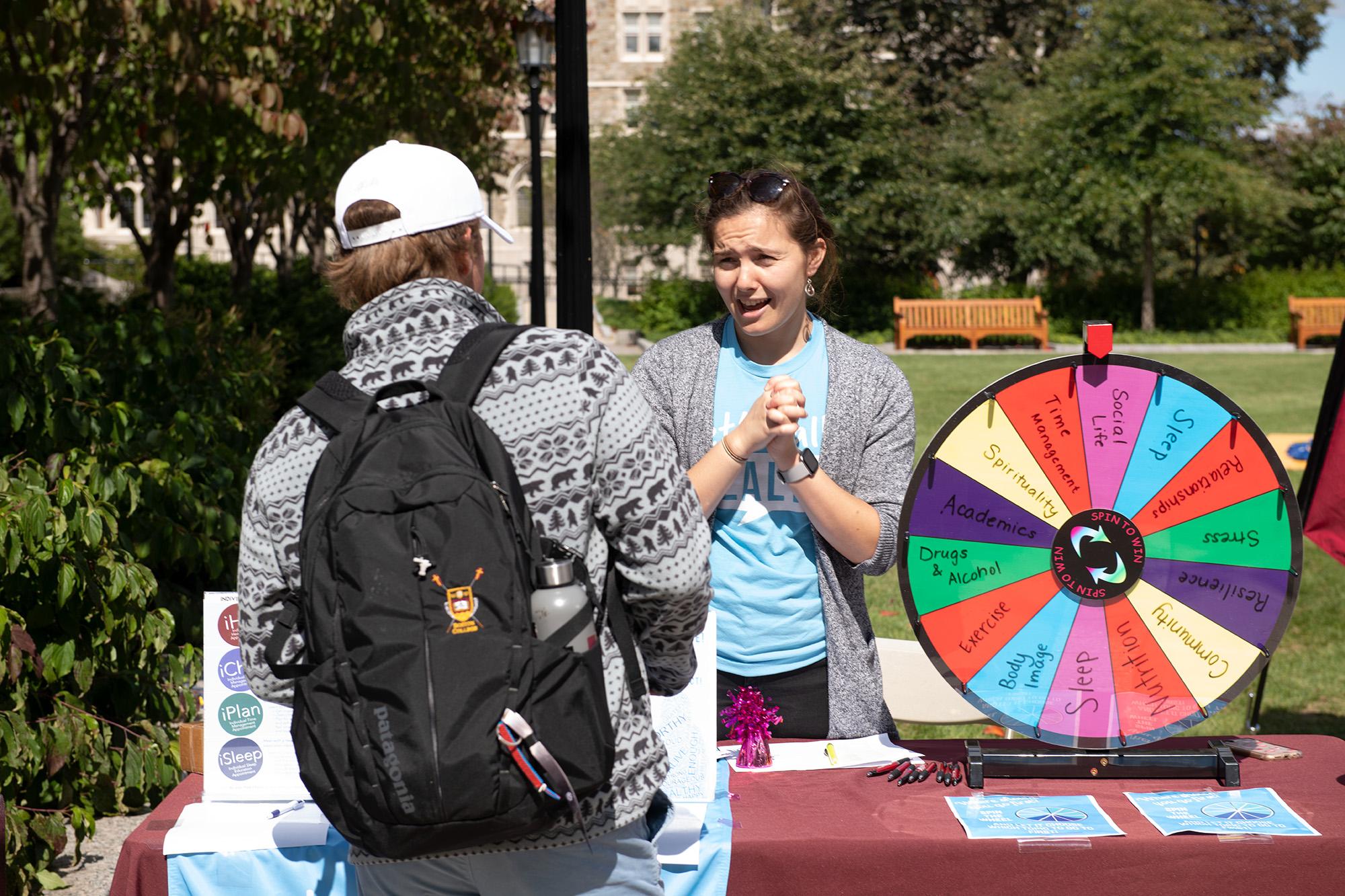 A woman standing behind a colorful wheel