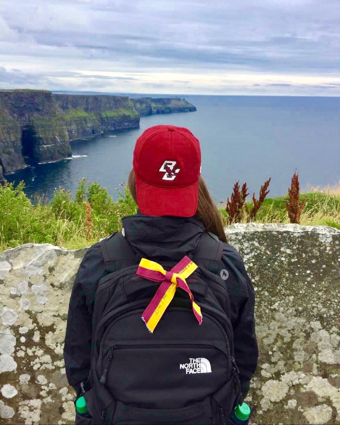 A student wearing a backwards BC hat looking at the Cliffs of Moher