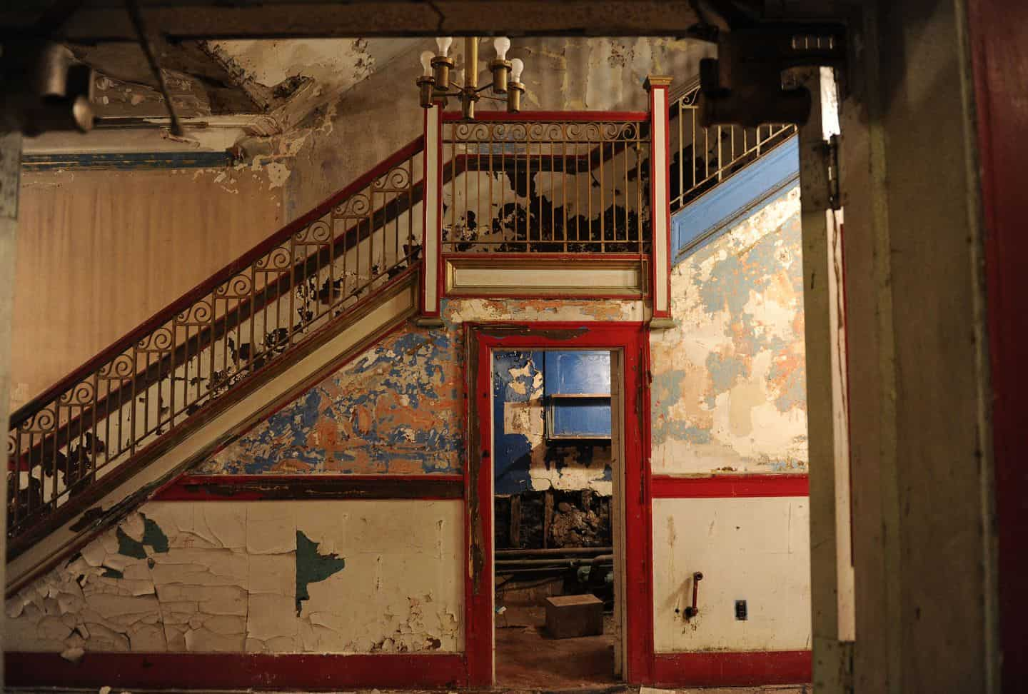 A decaying theater lobby with flaking paint and holes in the wall