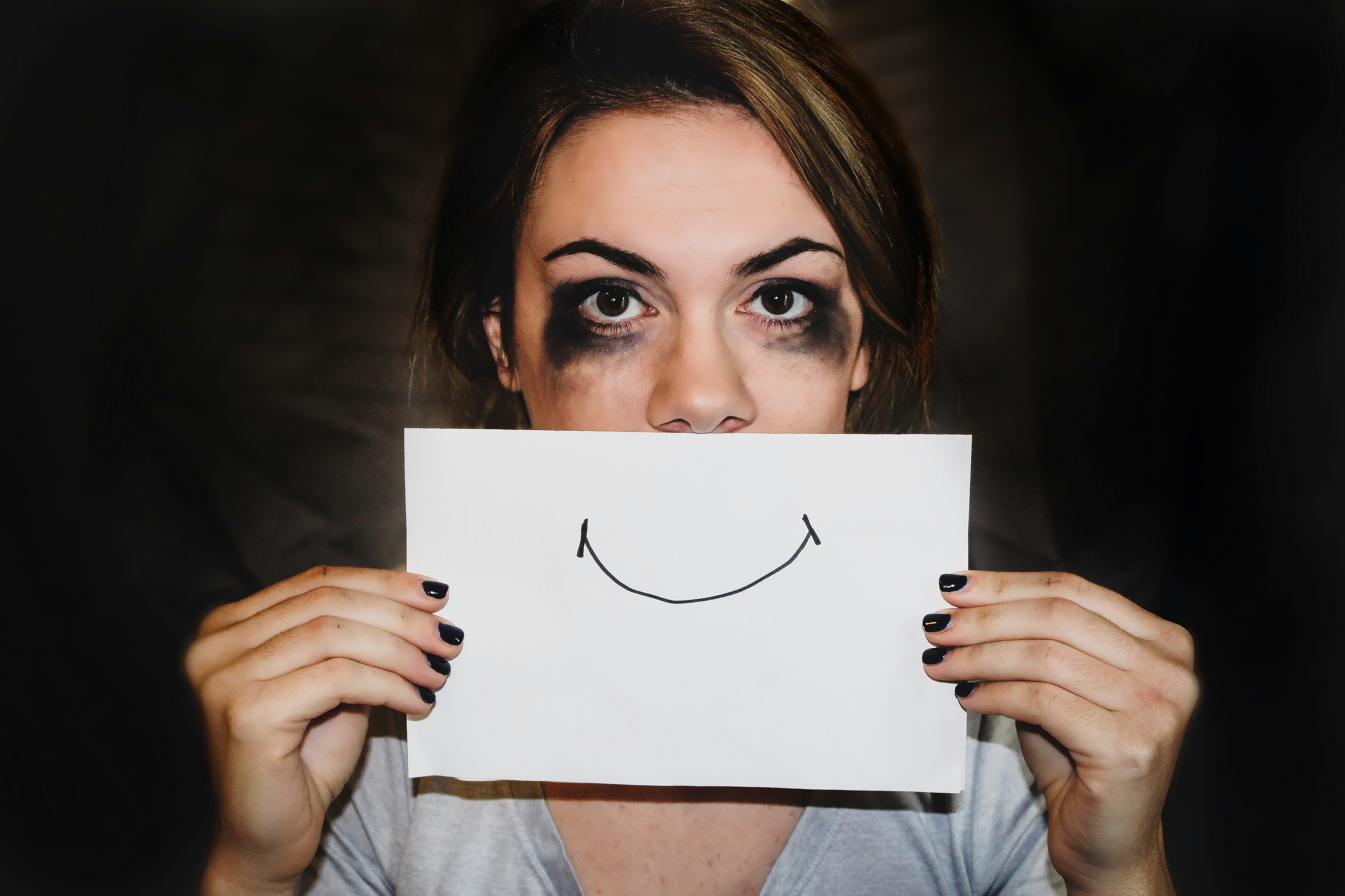 young woman holding a piece of paper with a smile drawn on it