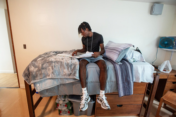 On the first day of orientation, a student pauses on his bed to review Messina materials.