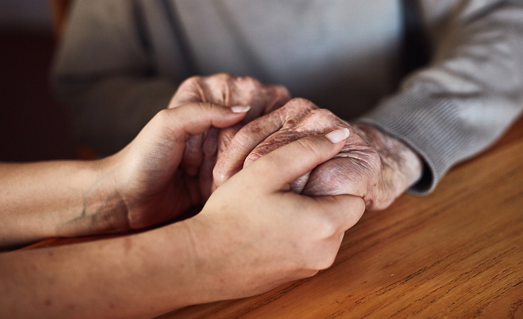 Two people, one older and one younger, holding hands