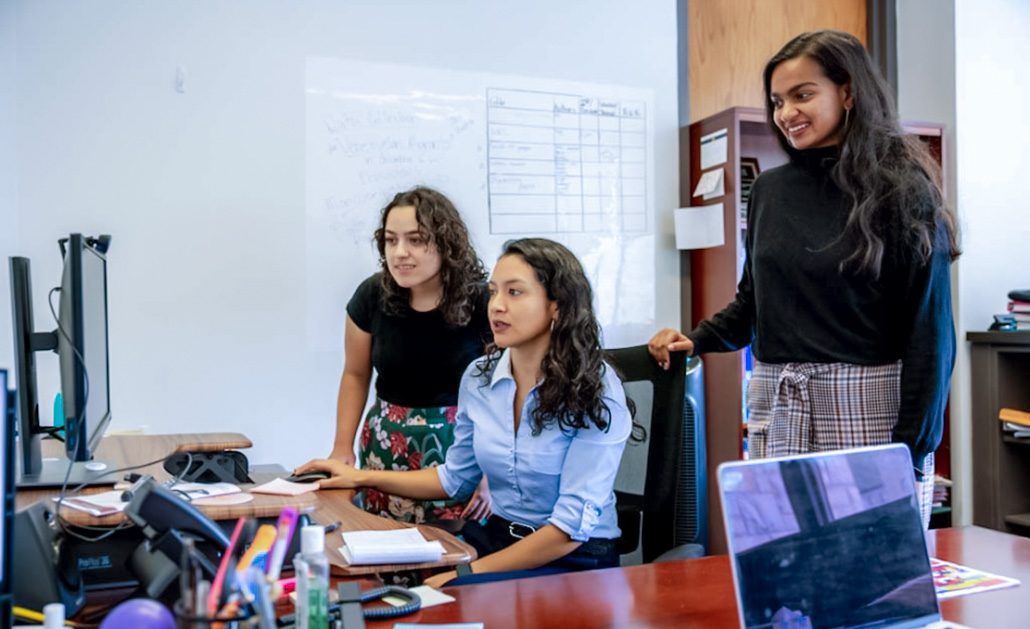 Two undergraduates chat with a faculty member in SSW