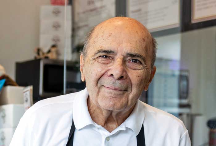 Photo of John Acampora at the counter of his Flat Breads shop