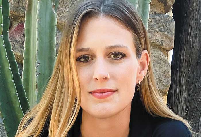 Elizabeth Flock photographed in front of cactus and stonewall.