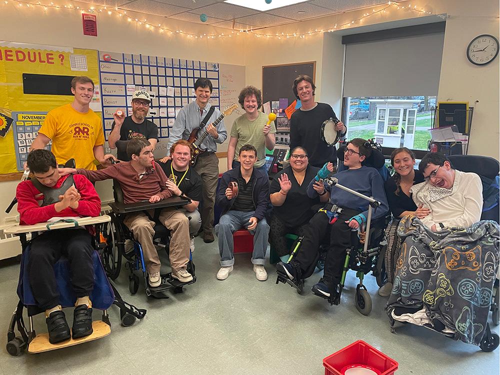 A classroom of teachers and students, some holding musical instruments