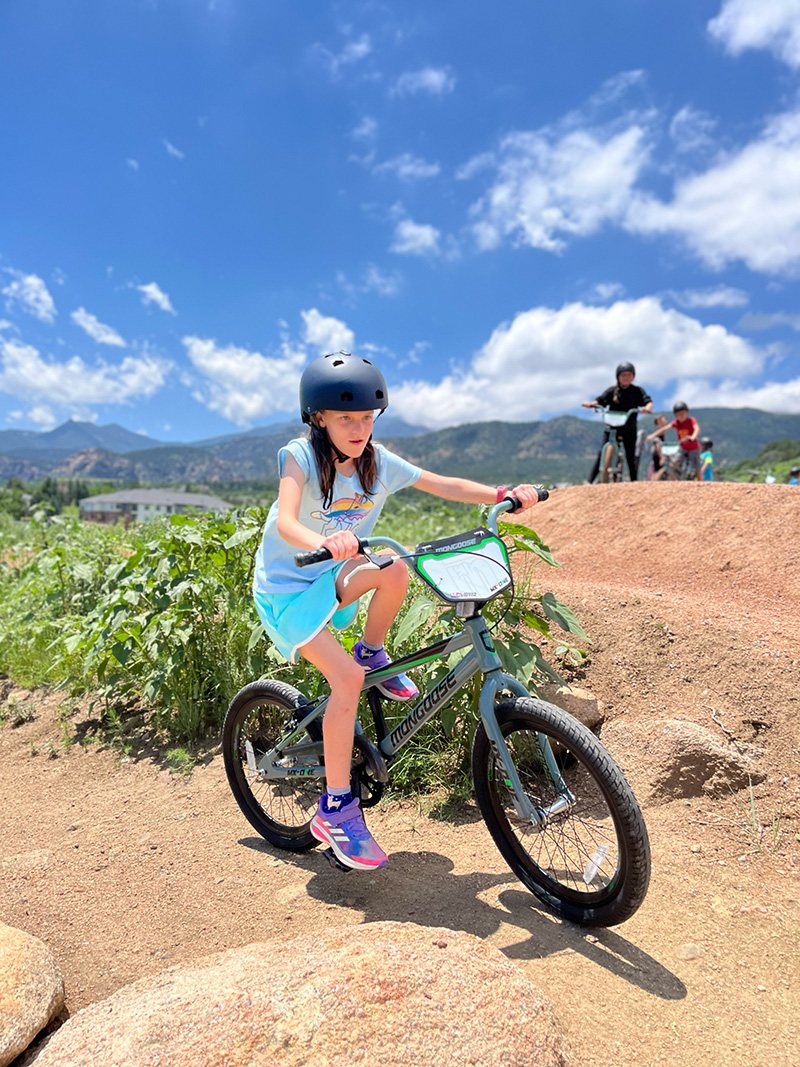 A young girl riding a bike on a dirt track
