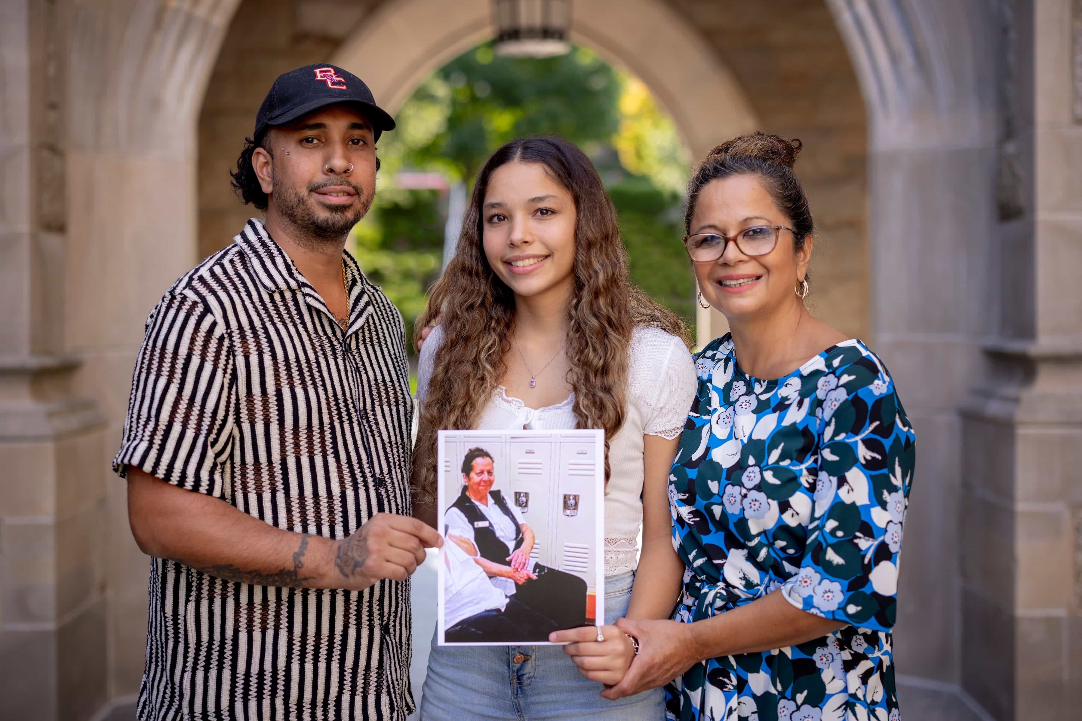 three people on campus, one holding a photograph