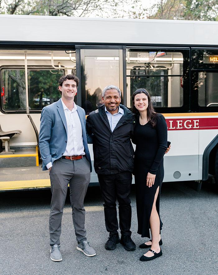 Three people standing in front of a shuttle bus
