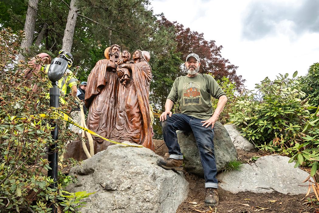 A crew lowers a statue onto a base