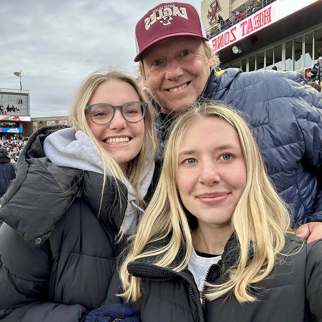 A man and two women at a football game in the stands