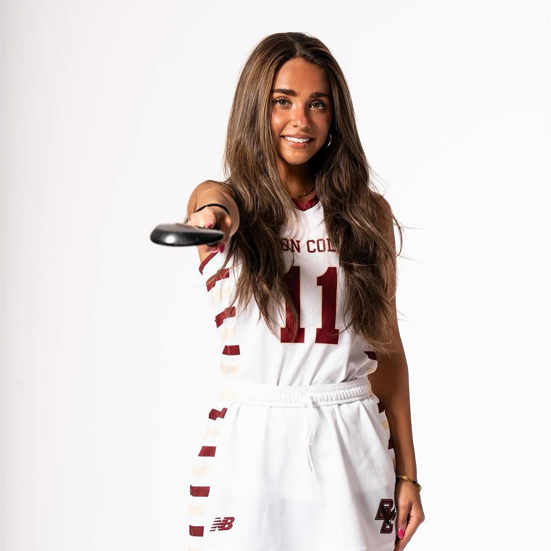 A woman in a BC uniform pointing a field hockey stick