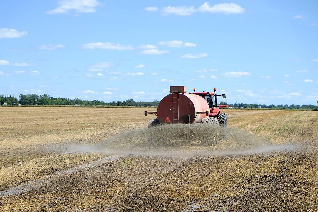 A truck spreads fertiilzer in a field