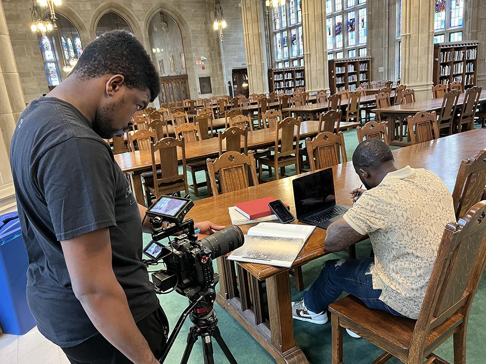A person being filmed while studying in the library